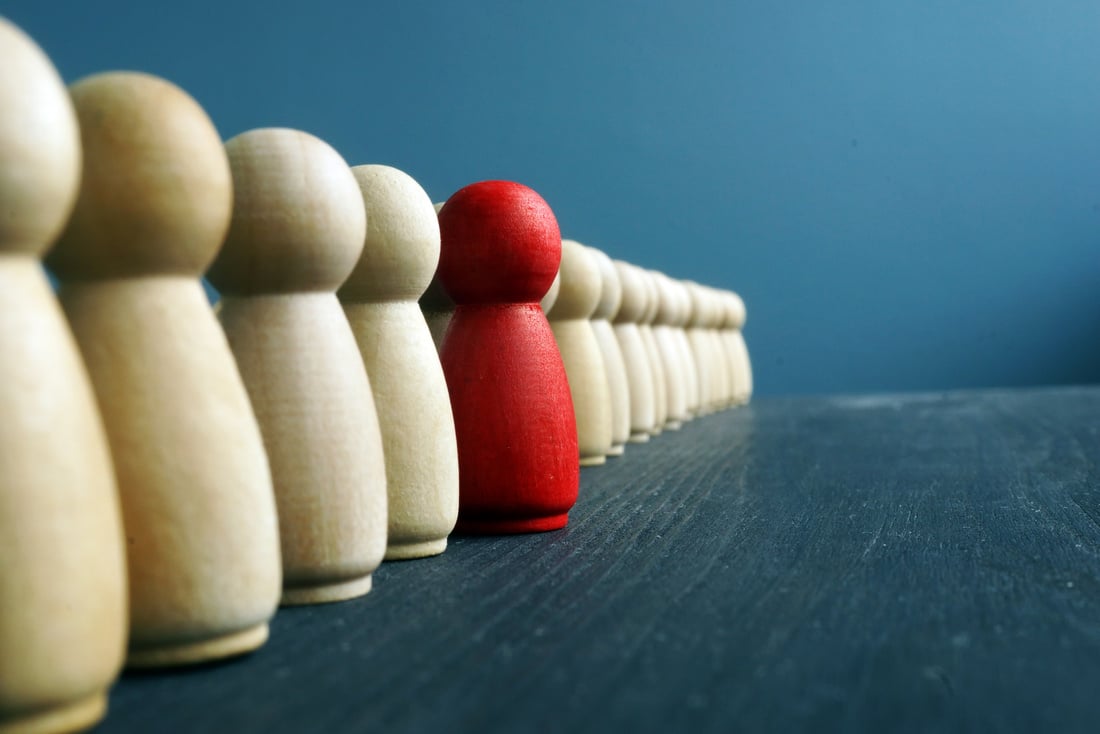 Leadership development. Line of wooden figurines with red one.